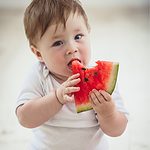 baby eating a slice of watermelon.