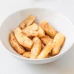 cinnamon sauted apple slices in a white bowl.