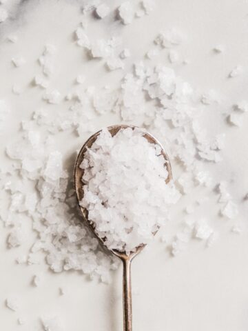 spoonful of salt on a white marble background.