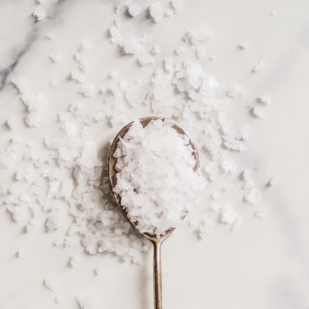 spoonful of salt on a white marble background.