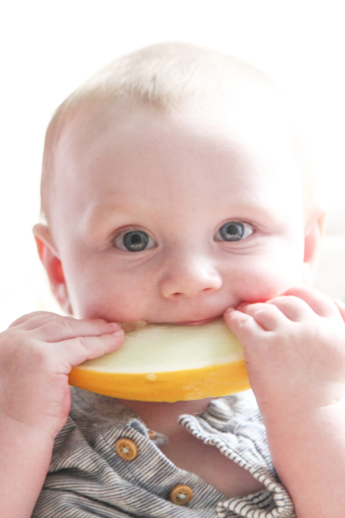 baby eating a wedge of melon.