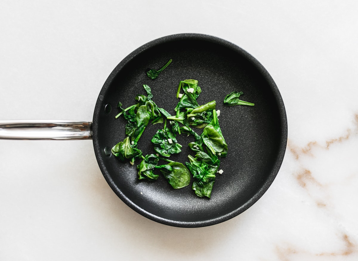 small skillet with sauted spinach in it.