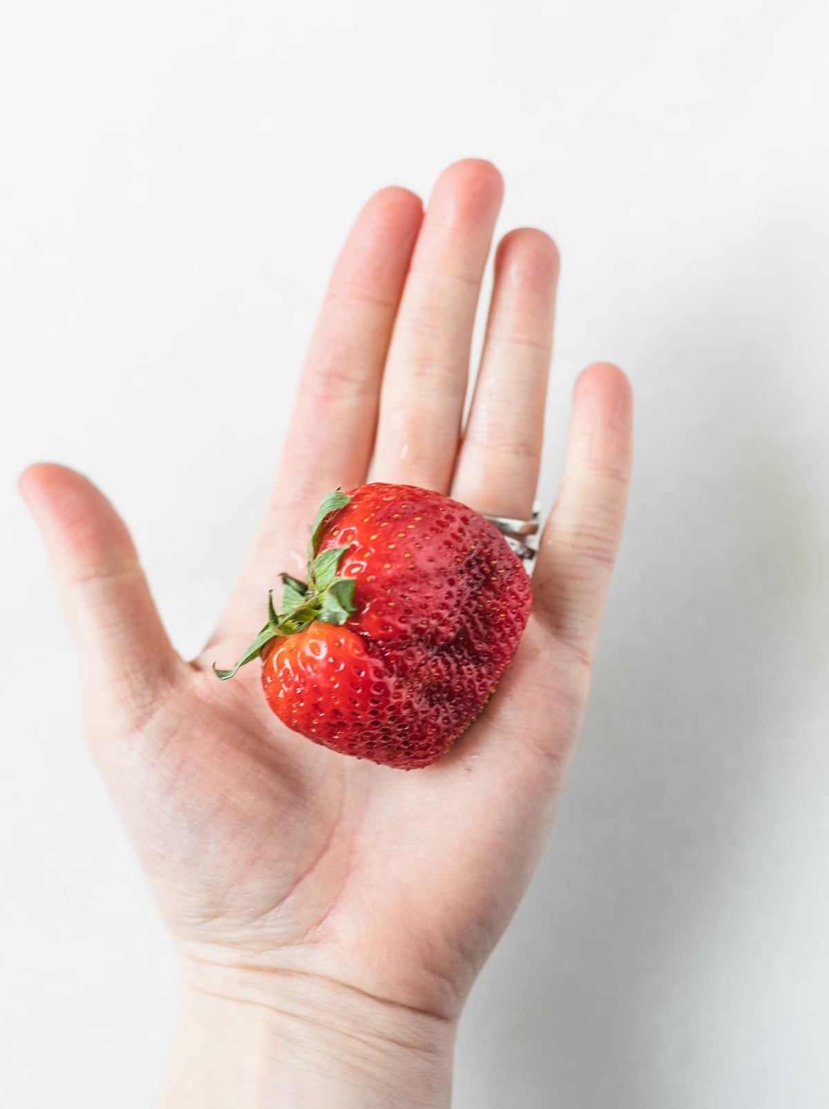 large, fresh strawberry in an open hand.