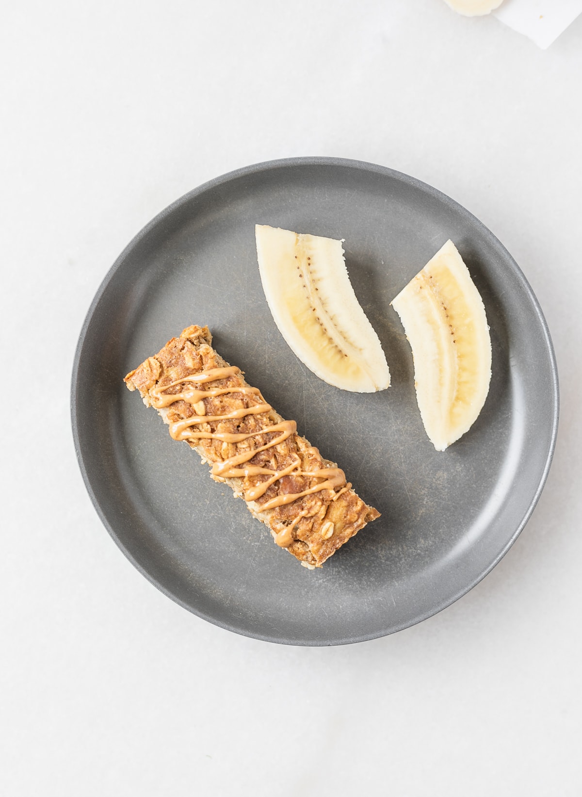 grey baby plate with peanut butter banana baked oatmeal cut into a strip and banana quarters.