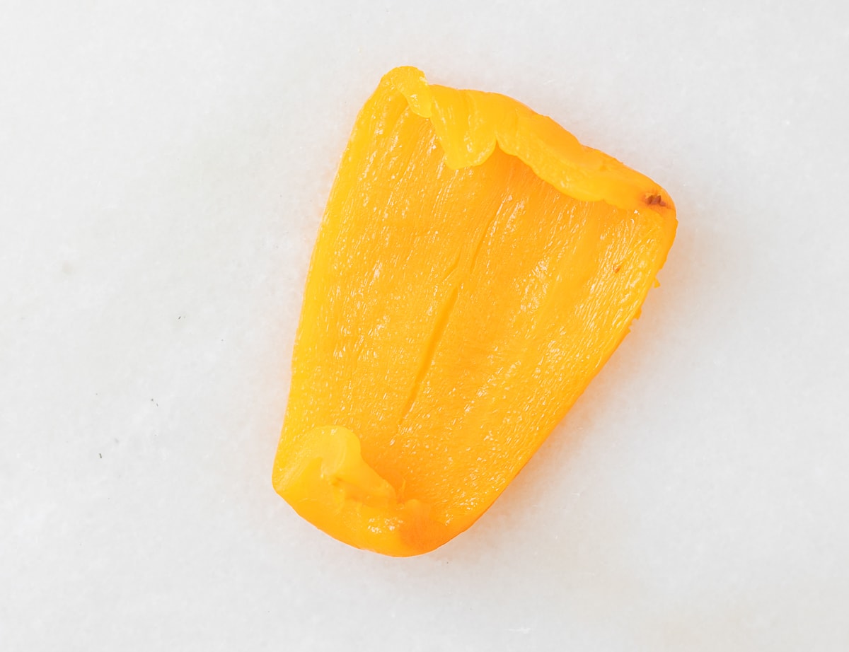 cooked third of an orange bell pepper on a white background.