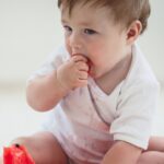 baby using palmar grasp to put watermelon in his mouth.