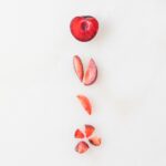 different ways of cutting plums for baby led weaning on a white background.