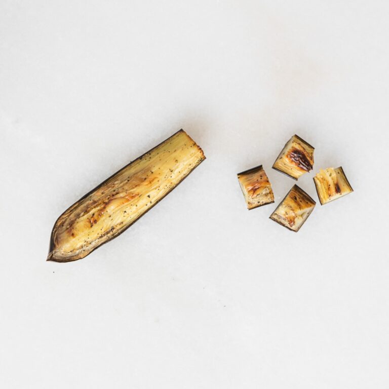 roasted eggplant cubes and spear on a marble background