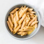 baby bowl of penne pasta with butternut squash pasta sauce.