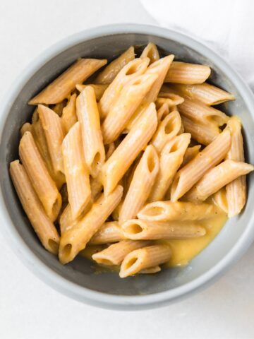 baby bowl of penne pasta with butternut squash pasta sauce.