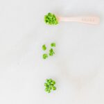 three ways of servings peas for babies on a white marble background.