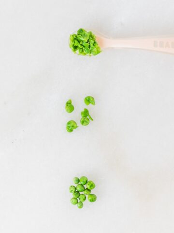 three ways of servings peas for babies on a white marble background.