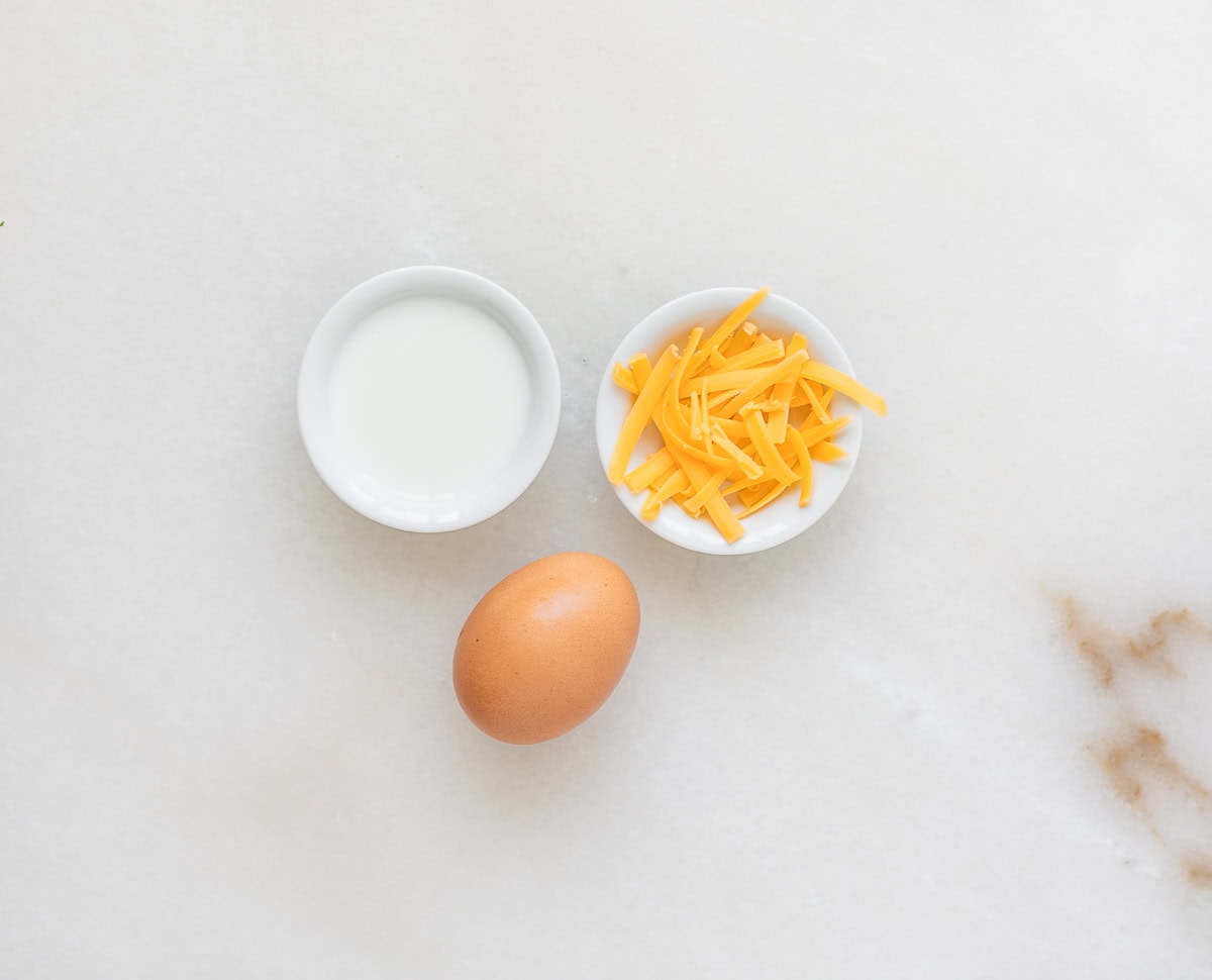 milk, shredded cheese and egg on a white background.