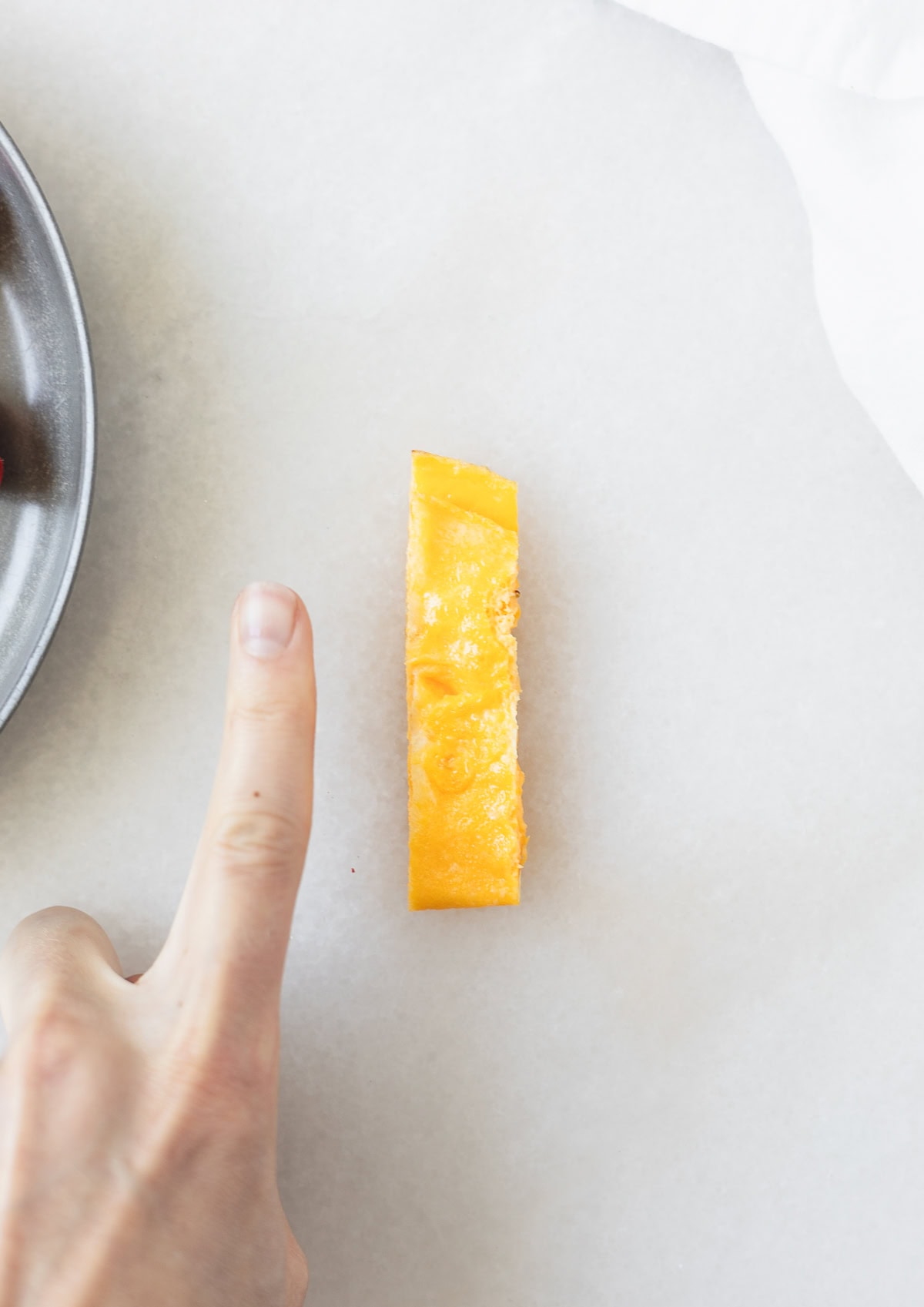 woman's finger next to a strip of baby omelet.