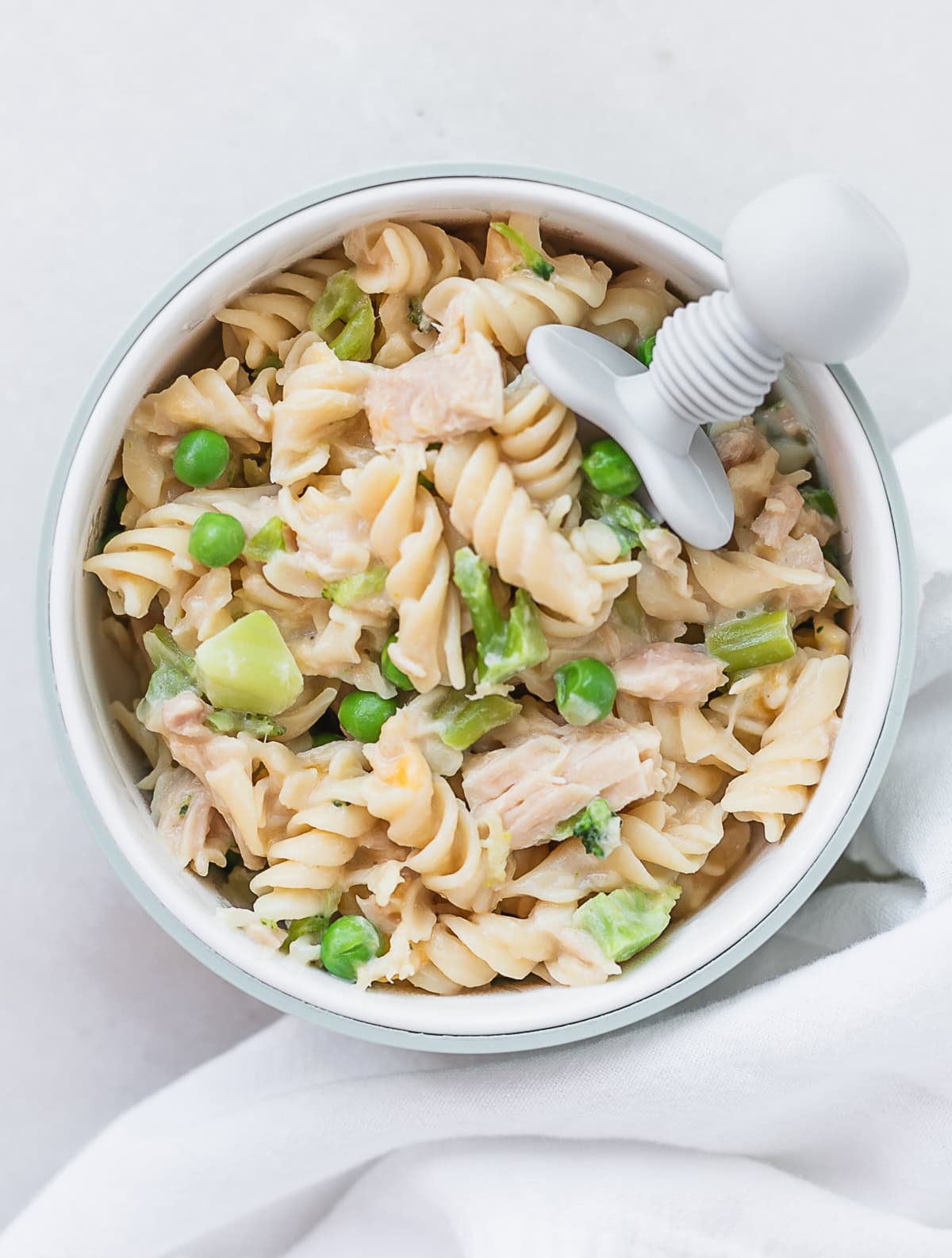 baby bowl with broccoli tuna and pea mac and cheese with a baby fork in it.