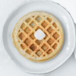 mini whole wheat waffle with a pat of butter on a plate.