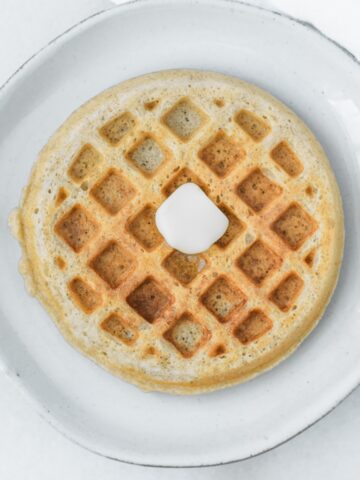 mini whole wheat waffle with a pat of butter on a plate.