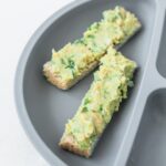 mashed chickpea avocado salad on two toast fingers on a baby plate.