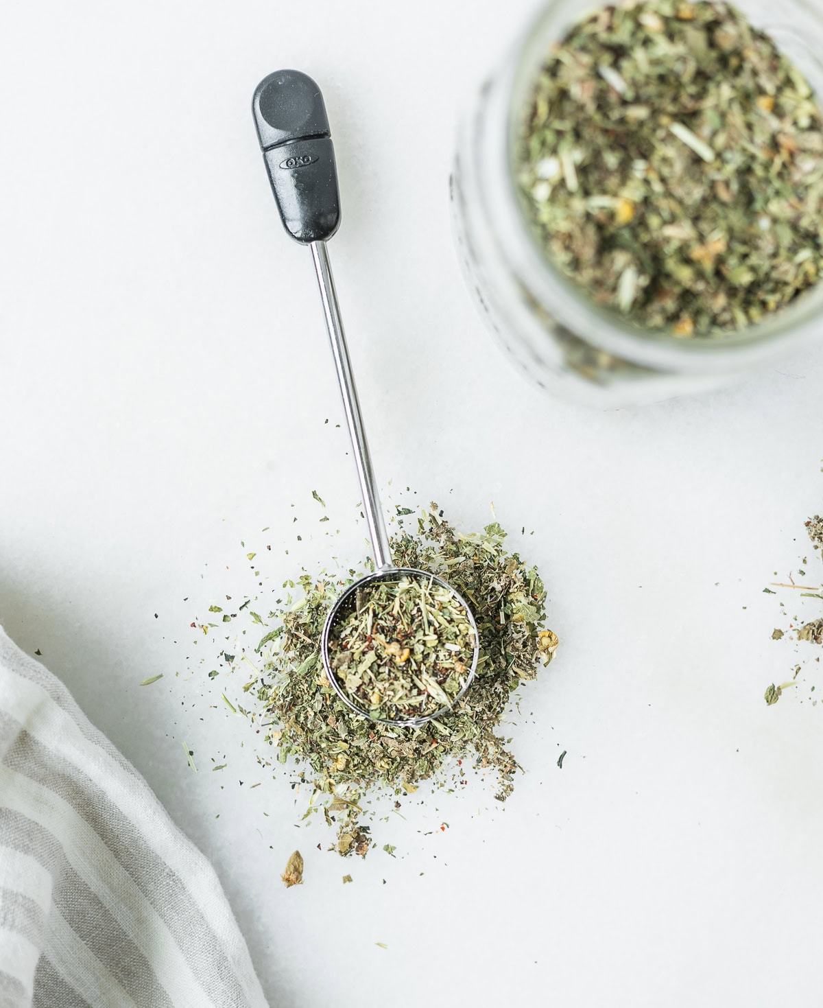tea strainer ball with pregnancy tea blend in it next to jar of herbal tea.