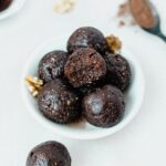 no bake prune brownie bites in a small bowl with a bite taken from the top one.