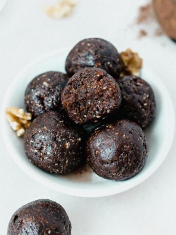 no bake prune brownie bites in a small bowl with a bite taken from the top one.