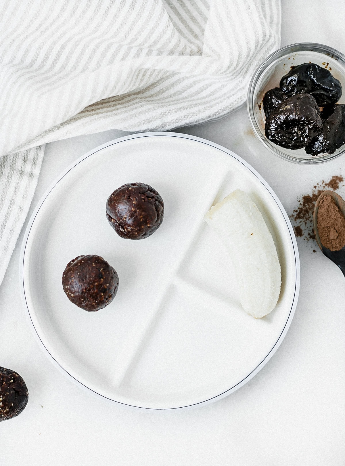 two prune brownie balls and a half banana on a baby plate.
