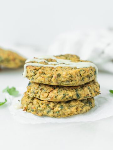 three stacked baked falafel drizzled with tahini sauce.