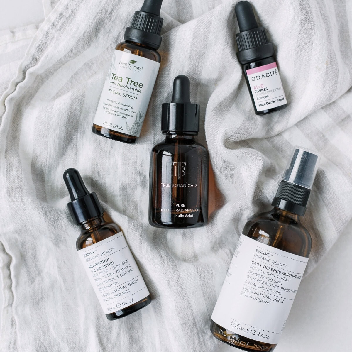skincare products in amber bottles on a striped linen towel.