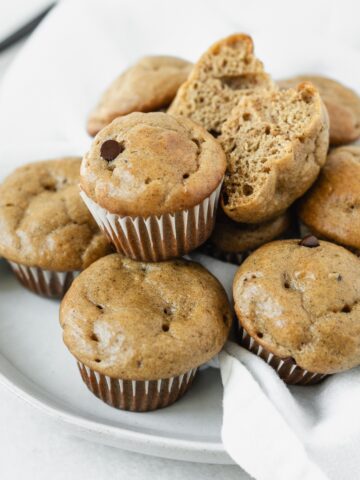 mini banana peanut butter protein muffins piled on a small plate.