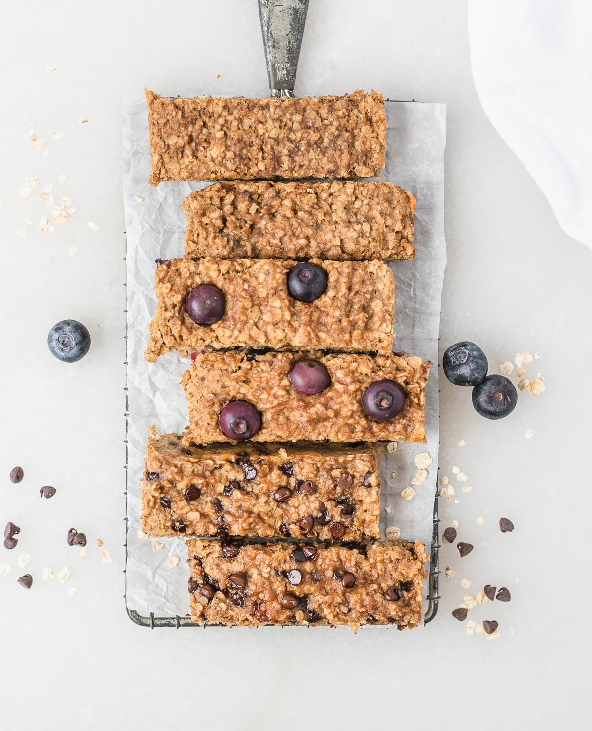 soft baked banana oatmeal bars with various mix-ins on a parchment covered wire rack.