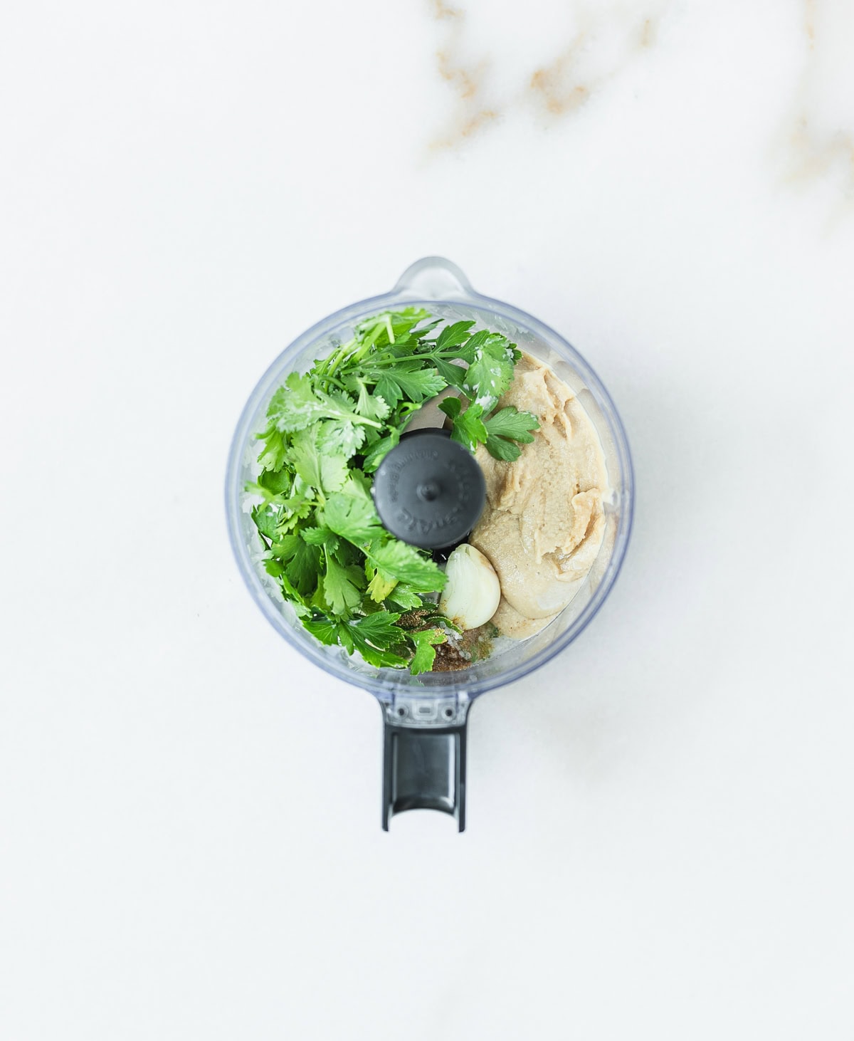 ingredients for herby green tahini sauce in a food processor before blending.