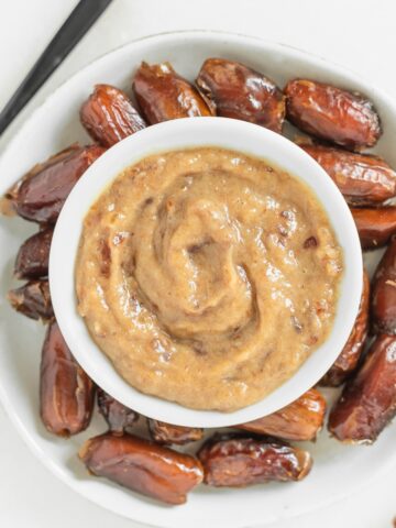 date caramel in a small bowl surrounded by dates on a plate.