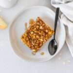 square of pumpkin apple baked oatmeal on a small plate with a black spoon.