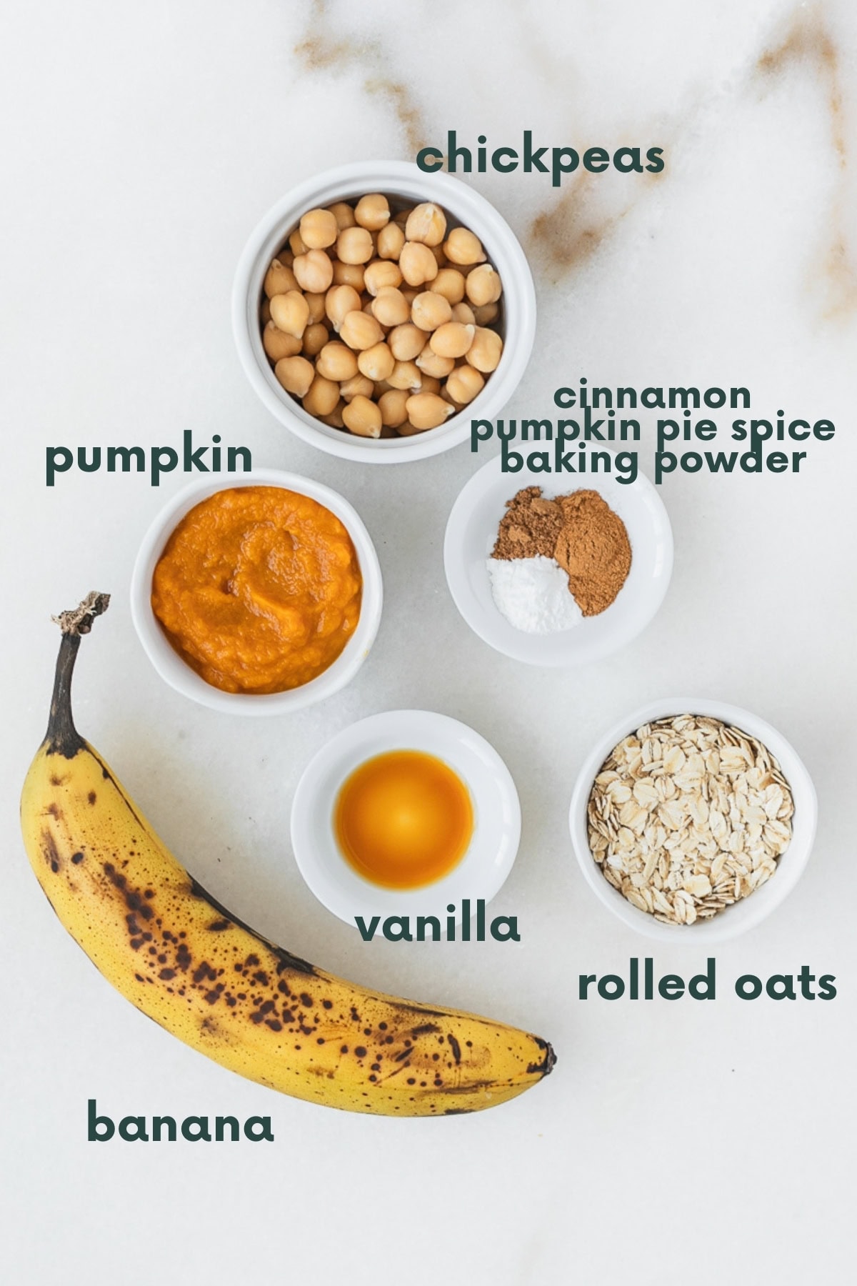 ingredients needed to make healthy pumpkin chickpea cookies on a white marble background with text overlay.