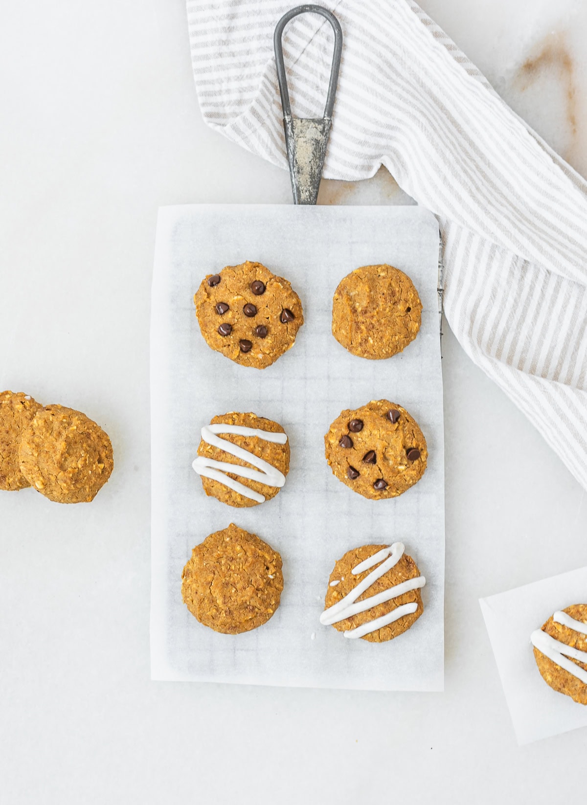 overhead view of pumpkin chickpea cookies, some with chocolate chips and some with yogurt drizzle on a wire rack.