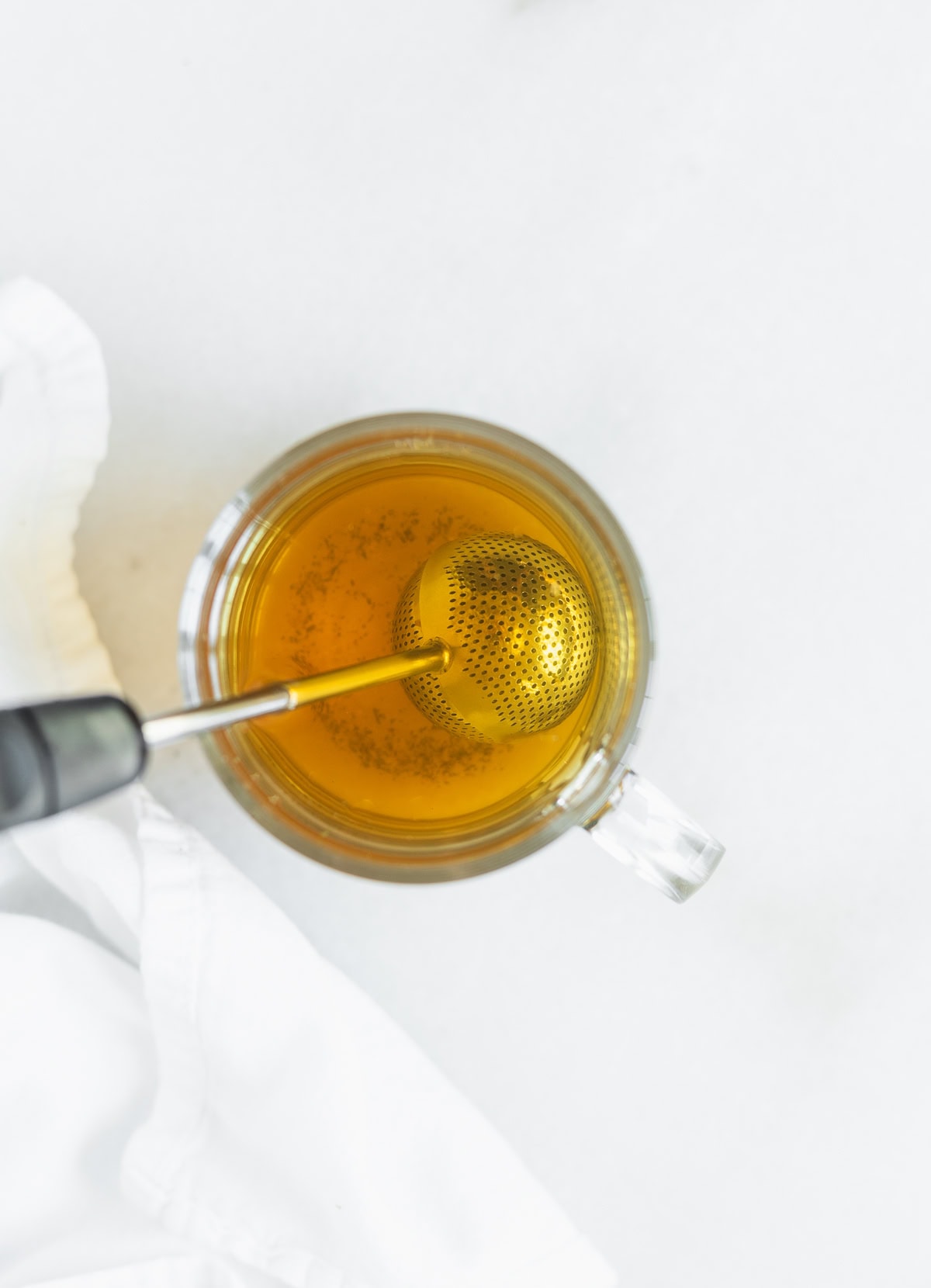 lactation tea being brewed in a glass mug with a tea ball.