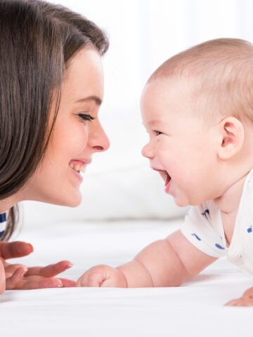 smiling mom facing a smiling baby on her belly.