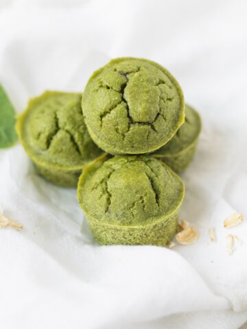mini green spinach muffins stacked on a white napkin.