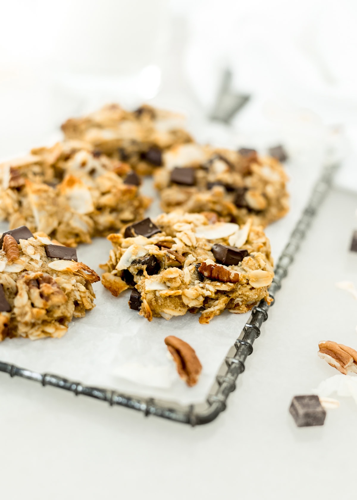 healthy lactation cookies on a cooling rack with pecans and chocolate chunks around them.