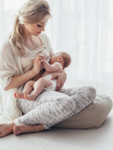 mom nursing baby on a floor pillow.