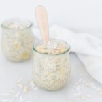 jar of pineapple coconut overnight oats with pink baby spoon in it.