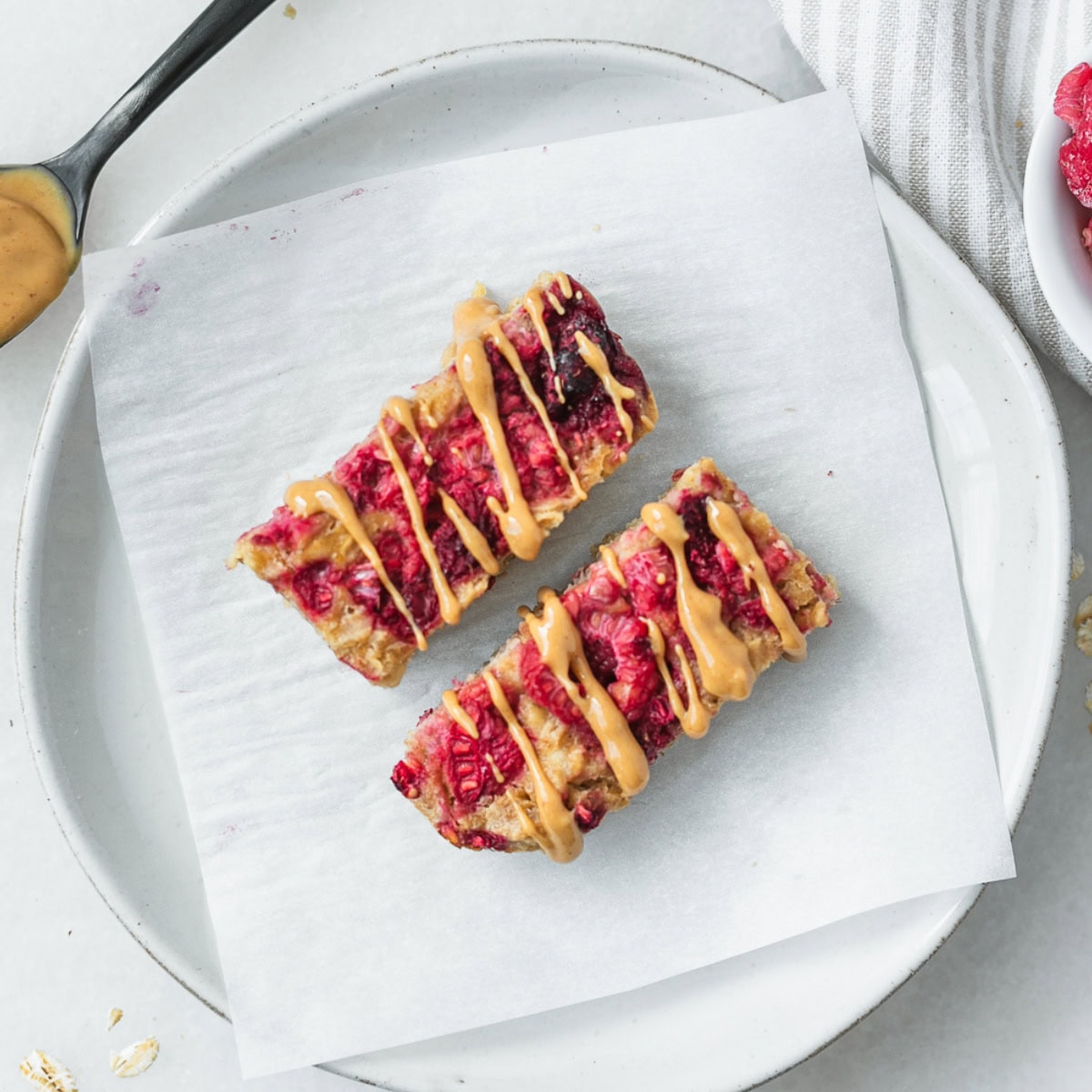 two baby pbj baked oatmeal bars for baby on a small white plate lined with parchment.
