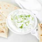 small white bowl of tzatziki sauce with pita wedges and a white napkin.