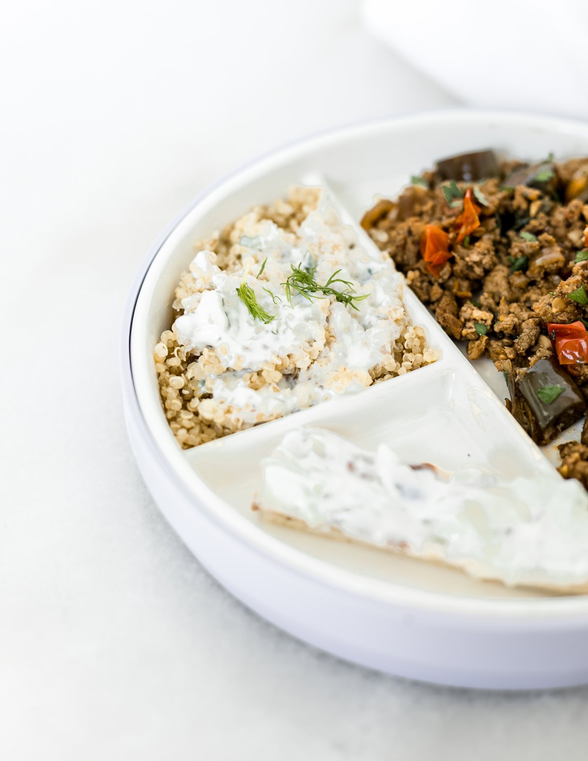 baby plate with pita fingers spread with tzatziki, quinoa topped with tzatziki and mediterranean beef stir fry.