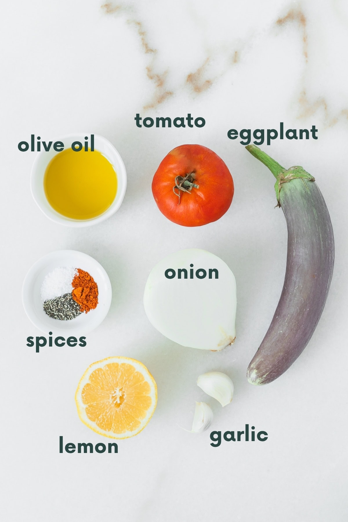 ingredients needed for roasted tomato eggplant dip on a white marble background with text overlay.