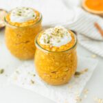 two jars of baby pumpkin spice overnight oats topped with yogurt and pumpkin seeds.